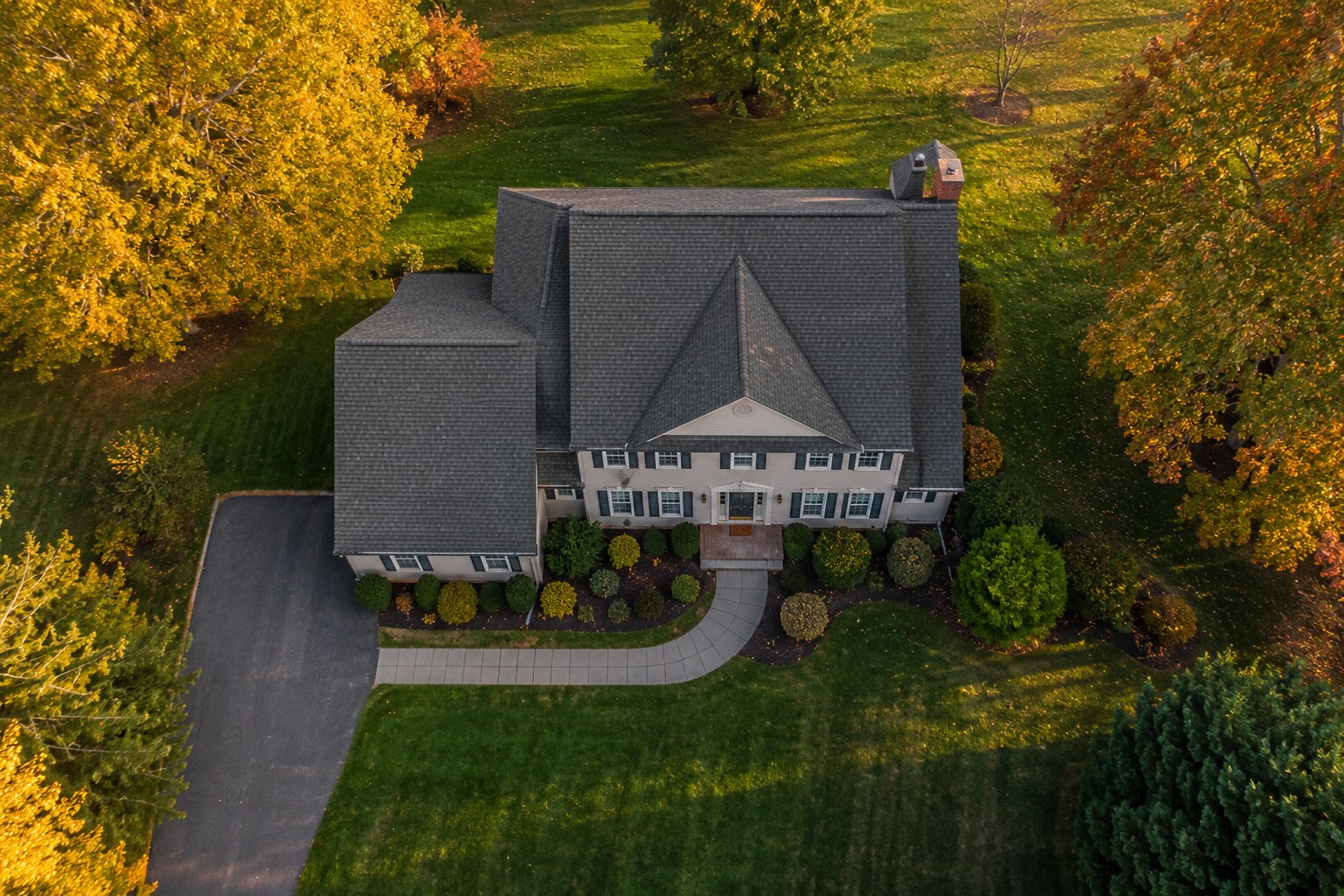 Top-down drone view of a suburban single-family home with autumn foliage
